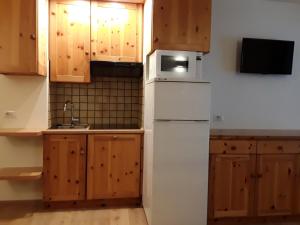 a kitchen with wooden cabinets and a white refrigerator at Apartments "STELLA ALPINA" in Santa Caterina Valfurva