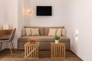 ein Wohnzimmer mit einem Sofa und 2 Tischen in der Unterkunft To Rantevou tis Alykis Rooms & Apartments in Kimolos