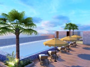 a pool with chairs and umbrellas next to a pool at Lemon Tree Premier, Vijayawada in Vijayawāda