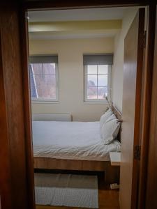 a small bedroom with a bed and two windows at STAR apartman Brzece Kopaonik in Brzeće