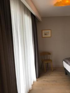 1 dormitorio con una ventana con cortinas blancas y una silla en LA COSTIERE DU LAC - ANNECY - Vieille ville, Plage, Garage en Annecy