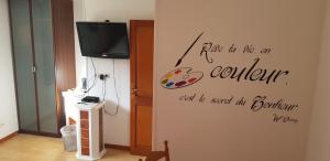 a living room with a tv and a wall with a quote at Maison Cancela in Siguer