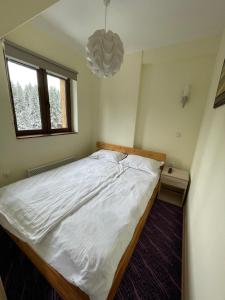 a bedroom with a large white bed with a chandelier at Apartment Koko in Kopaonik