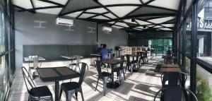 um restaurante com mesas e cadeiras e uma pessoa ao fundo em The chess hotel em Rayong