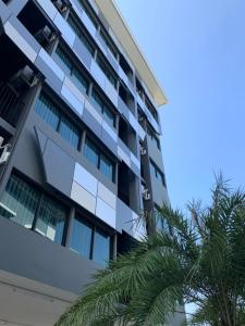 un edificio de apartamentos con palmeras delante en The chess hotel en Rayong