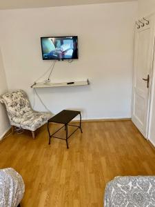 uma sala de estar com uma cadeira e uma televisão na parede em Gemütliches WG-Zimmer 5, zentral in Ravensburg (stadtnah) em Ravensburg