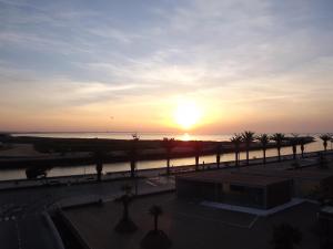 un coucher de soleil sur l'eau avec des palmiers et un bâtiment dans l'établissement Hotel Mar Azul, à Lagos