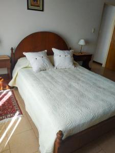 1 cama grande con sábanas y almohadas blancas en Departamentos Arco Iris Tandil en Tandil