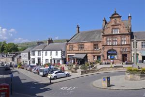 a town with cars parked in front of a building at The TEVIOT in the centre of Melrose in Melrose