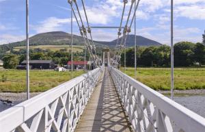 un puente sobre un río con una montaña en el fondo en The Teviot in the centre of Melrose en Melrose