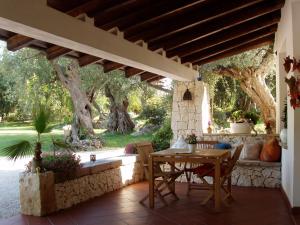 un patio con mesa, sillas y árboles en Alba Bed & Breakfast, en Melendugno
