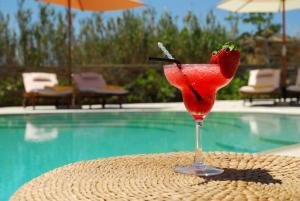 a strawberry drink sitting on a table next to a pool at Anthea Hotel in Tinos Town