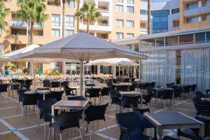 taras ze stołami, krzesłami i parasolem w obiekcie Hotel Neptuno by ON Hotels Group w mieście Roquetas de Mar