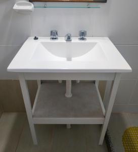 a white sink with two faucets in a bathroom at Departamentos Arco Iris Tandil in Tandil