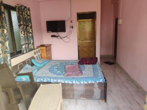 a small bedroom with a bed and a tv at Gulmohar Cottages - Home Stay in Alibag in Alibaug