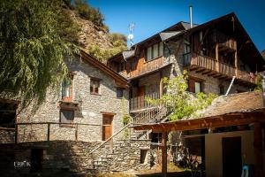a large stone building with a balcony on the side at Camping Bungalows La Borda del Pubill in Ribera de Cardós