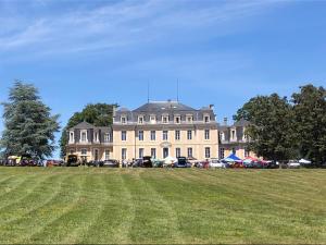 un gran edificio con un campo de césped delante de él en chambre romantique dans le château de la Bouchatte en Chazemais
