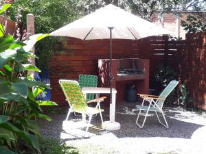 una mesa y sillas bajo una sombrilla en un patio en cabañas La Victoria en La Falda