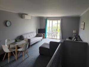 ein Wohnzimmer mit einem Sofa und einem Tisch in der Unterkunft Aqualuna Apartments in Coffs Harbour