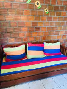 - un banc en bois avec 4 oreillers colorés dans l'établissement Chalé Brisa de Gravatá, à Gravatá