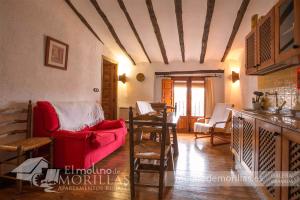 Una sala de estar con un sofá rojo y una mesa. en Apartamentos Rurales El Molino De Morillas, en Galera