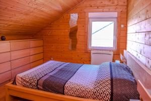 ein Schlafzimmer mit einem Bett in einer Holzhütte in der Unterkunft Insolite maison bois, wifi Netflix, au coeur de l'Argonne et des batailles de Verdun in Chaudefontaine
