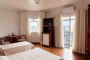 a hotel room with two beds and a flat screen tv at Castelar Novo Hotel in Varginha