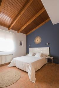 1 dormitorio con 1 cama blanca grande y pared azul en Casa turística Me quedo en el pueblo, en Muñana