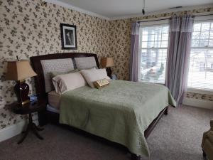 a bedroom with a bed with a green comforter and two windows at The Nordic Pineapple Bed and Breakfast in Saint Johns
