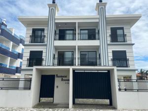 a white building with two columns and a garage at Hostel APÊ DO CRIS in Florianópolis