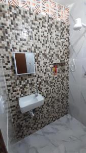 卡拉瓜塔图巴A Casa da Praia的带水槽和墙上电视的浴室