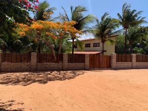a fence in front of a house with palm trees at Loft Jeri in Jericoacoara