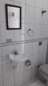 La salle de bains est pourvue d'un lavabo, d'un miroir et de toilettes. dans l'établissement Apto Pé na Areia, à São Vicente