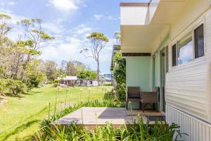 - une vue depuis la terrasse couverte d'une maison avec une cour dans l'établissement Surfside Cudmirrah Beach, à Berrara