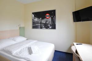 a bedroom with a white bed and a television at Best Deal Airporthotel Weeze in Weeze