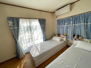 um quarto com 2 camas e uma janela com cortinas azuis em 次郎の家 em Fuefuki