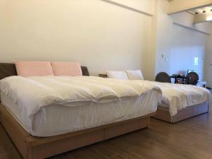 a bedroom with a large bed with white sheets and pink pillows at Sanyi Happiness B&B in Sanyi