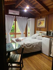 ein Schlafzimmer mit einem Bett und einem Tisch und einem Fenster in der Unterkunft Pousada e Hostel Vale do Rosa in Praia do Rosa