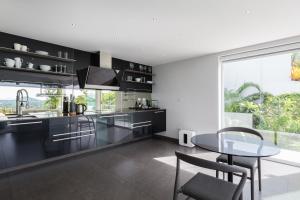 une cuisine avec des armoires noires et une table en verre dans l'établissement Villa Sasipimon - Panoramic Duplex Studio, à Chaweng Noi Beach