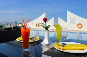 a table with plates and drinks on it with a pool at Skylark Hotel Apartments AL Barsha in Dubai