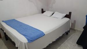 Una gran cama blanca con una manta azul. en Tharuka Rest Inn Hotel, en Tanamalwila