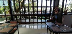 two wooden tables in a room with windows at Sun smile(cafe & homestay) in Ubon Ratchathani