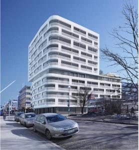 un gran edificio blanco con coches estacionados frente a él en New and cozy apartment in the centrum of Oulu, en Oulu