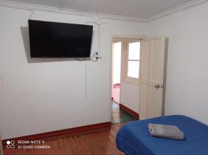 Habitación con TV de pantalla plana en la pared en Hospedaje curicó casa grande, en Curicó
