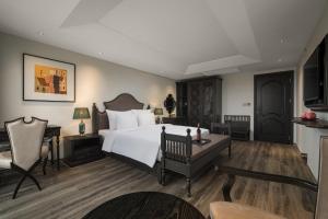 um quarto com uma grande cama branca e uma secretária em Lalita Boutique Hotel & Spa Ninh Binh em Ninh Binh