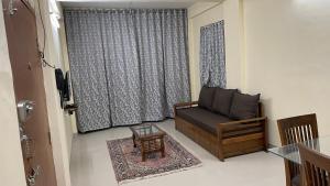 ein Wohnzimmer mit einem Sofa und einem Fenster in der Unterkunft Belle-Vue Holiday Homes in Panchgani