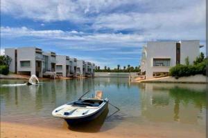 una barca seduta in acqua di fronte alle case di Appt Bouznika EDEN ISLAND pied sur Mer a Bouznika
