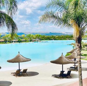 a pool with chairs and umbrellas and a beach at The Blyde 104 in Pretoria
