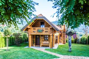 uma cabana de madeira com um alpendre num quintal em Village Cottage - Koča na vasi em Nazarje