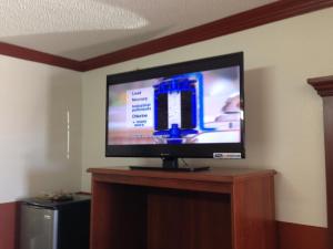 TV de pantalla plana en la parte superior de un soporte de madera en Executive Inn Robstown, en Robstown